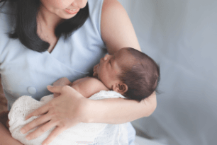 お母さんが笑顔で新生児を抱っこしている写真